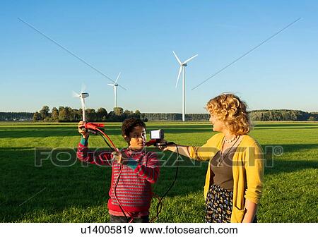 Stock Photo - Teenage boy and girl experimenting with sustainable energy by wind turbines, Netherlands. Fotosearch