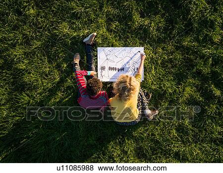 Teenage boy and girl on grass experimenting and drawing sustainable energy solutions, overhead view View Large Photo Image Stock Photo - Teenage boy and girl on grass experimenting and drawing sustainable energy solutions, overhead view. Fotosearch