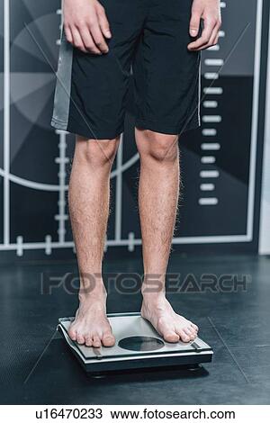Stock Image - Teenage boy on weighing scales. Fotosearch