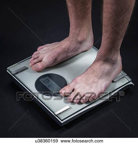 Stock Photo - Teenage boy on weighing scales. Fotosearch