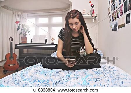 Picture - Teenager social networking on bed. Fotosearch