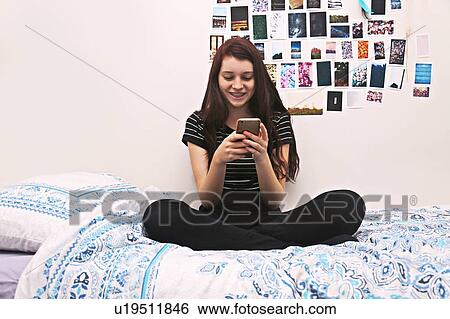 Stock Photograph - Teenager social networking on bed. Fotosearch