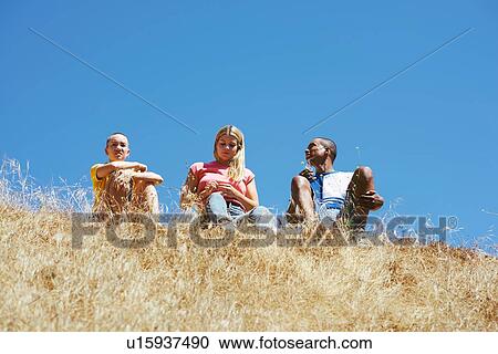 Three young adult friends sitting on top of hill in park, low angle view, Los Angeles, California, USA View Large Photo Image Stock Image - Three young adult friends sitting on top of hill in park, low angle view, Los Angeles, California, USA. Fotosearch