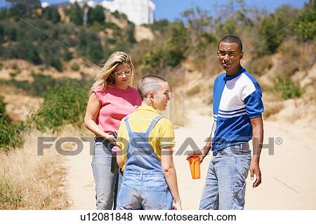 Stock Photo - Three young adult friends standing on dirt track, Los Angeles, California, USA. Fotosearch
