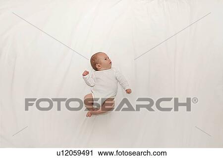 Stock Image - Tiny baby on spacious bed. Fotosearch