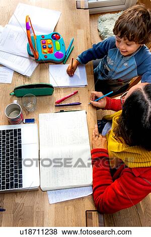 Stock Photo - Toddler boy learning from mother working from home. Fotosearch