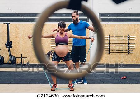 Trainer guiding pregnant woman using ropes in gym View Large Photo Image Stock Image - Trainer guiding pregnant woman using ropes in gym. Fotosearch