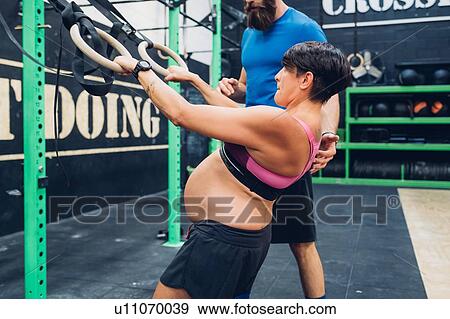 Trainer guiding pregnant woman using exercise equipment in gym View Large Photo Image Stock Photo - Trainer guiding pregnant woman using exercise equipment in gym. Fotosearch