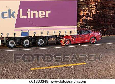 Stock Photo - Two cars accident. Crashed cars. A red car against the back of a big truck. Big damage. On the road with environment background.. Fotosearch