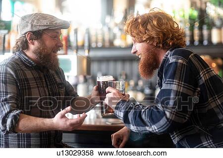 Two male customers making a toast in traditional Irish public house View Large Photo Image Stock Photo - Two male customers making a toast in traditional Irish public house. Fotosearch
