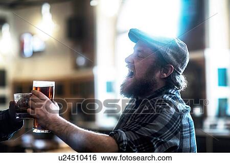 Stock Photograph - Two male customers making a toast in traditional Irish public house. Fotosearch