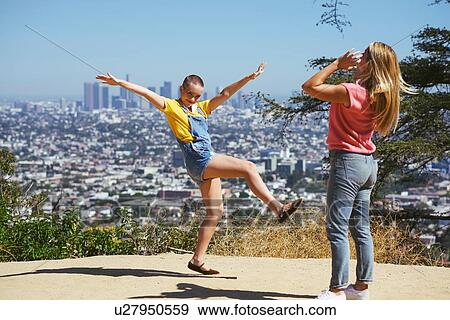 Stock Photo - Two young female friends having fun on cityscape hilltop, Los Angeles, California, USA. Fotosearch