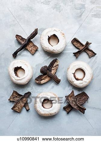 Stock Image - Variety of mushrooms arranged in noughts and crosses. Fotosearch