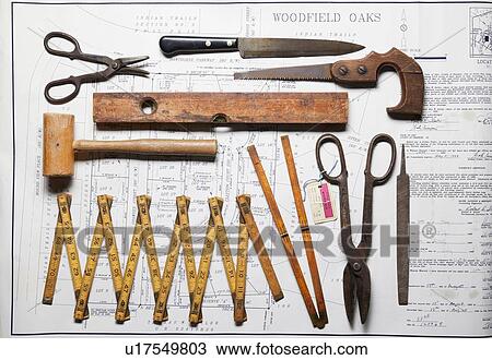 Stock Image - Variety of vintage hand tools on property map, overhead view. Fotosearch