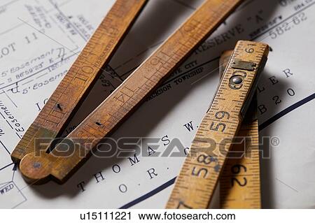 Stock Image - Vintage rulers on property map, close up. Fotosearch