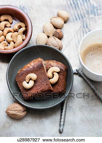 Stock Photo - Walnuts in shell, cashew nuts, cake slices and coffee. Fotosearch