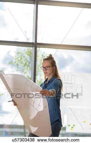 Stock Photo - Woman contemplating plans by glass wall. Fotosearch