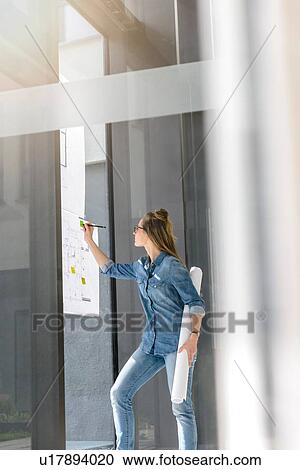Woman contemplating plans on glass wall View Large Photo Image Stock Image - Woman contemplating plans on glass wall. Fotosearch