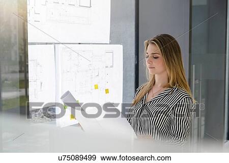 Woman contemplating plans on glass wall View Large Photo Image Stock Photo - Woman contemplating plans on glass wall. Fotosearch