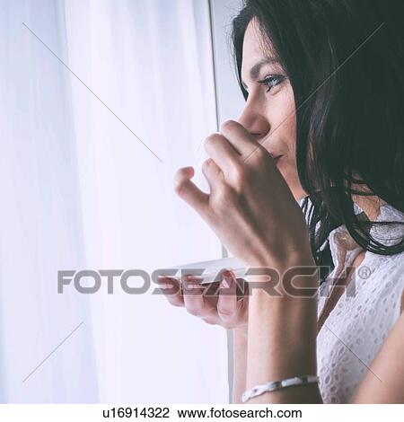 Woman drinking coffee beside window View Large Photo Image Stock Image - Woman drinking coffee beside window. Fotosearch