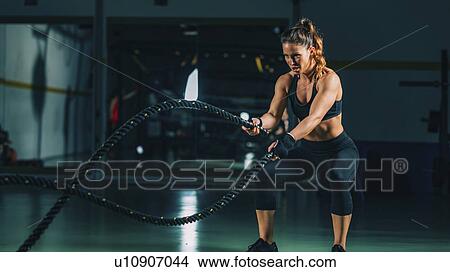 Picture - Woman exercising with battle ropes. Fotosearch