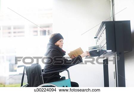 Picture - Woman in wheelchair getting post from post box. Fotosearch