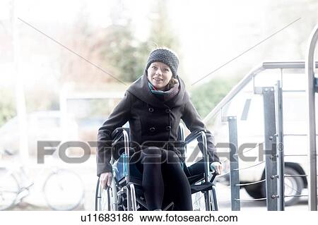 Stock Photograph - Woman in wheelchair moving up ramp. Fotosearch