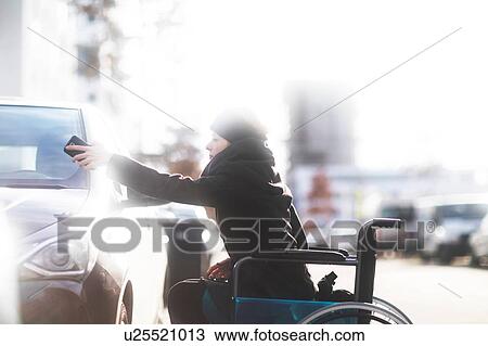 Stock Image - Woman in wheelchair using cellphone as remote control. Fotosearch