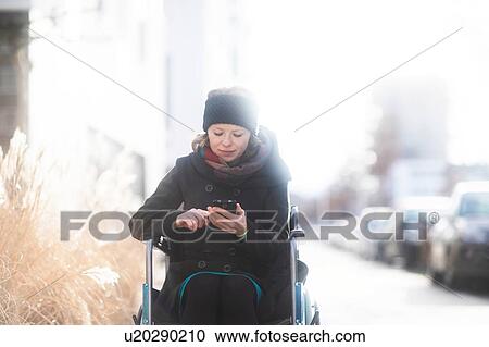 Woman in wheelchair using cellphone in street View Large Photo Image Stock Image - Woman in wheelchair using cellphone in street. Fotosearch