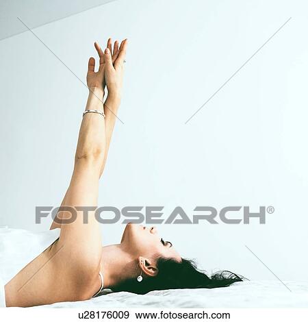 Stock Photo - Woman lying on back stretching. Fotosearch