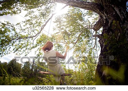 Stock Photo - Woman on swing in forest. Fotosearch