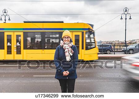 Stock Photo - Woman posing on roadside, tram passing by in background, Budapest, Hungary. Fotosearch
