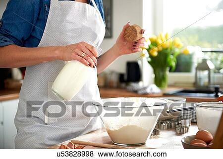 Woman pouring milk into mixing bowl in kitchen View Large Photo Image Stock Photo - Woman pouring milk into mixing bowl in kitchen. Fotosearch