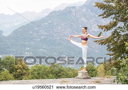 Woman practicing yoga, balancing on one leg on top of plinth, mountain landscape, Domodossola, Piemonte, Italy View Large Photo Image Stock Image - Woman practicing yoga, balancing on one leg on top of plinth, mountain landscape, Domodossola, Piemonte, Italy. Fotosearch