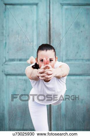 Woman practicing yoga, on one leg in front of door, portrait View Large Photo Image Stock Image - Woman practicing yoga, on one leg in front of door, portrait. Fotosearch