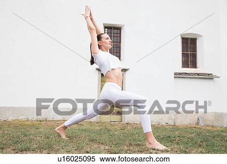 Woman practicing yoga, warrior pose in front of building View Large Photo Image Stock Photography - Woman practicing yoga, warrior pose in front of building. Fotosearch