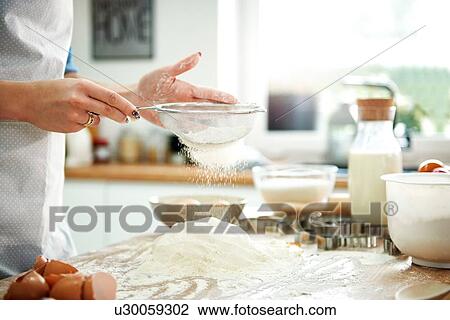 Woman sifting flour in kitchen View Large Photo Image Stock Image - Woman sifting flour in kitchen. Fotosearch