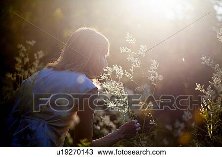 Stock Image - Woman smelling flowers in forest. Fotosearch