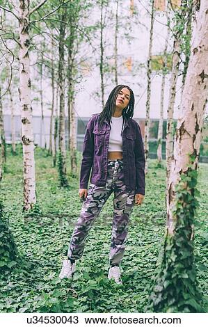 Stock Image - Woman standing on ivy among silver birch trees. Fotosearch