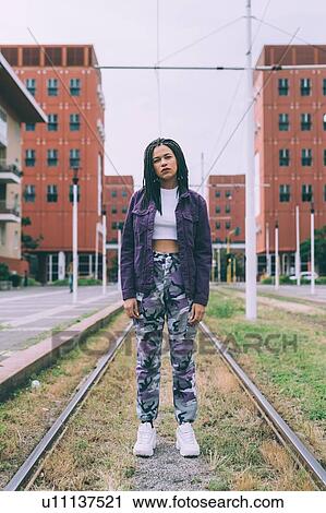 Stock Image - Woman standing on tram tracks, Milan, Italy. Fotosearch