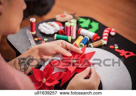 Woman stitching felt poinsettia onto christmas decoration, over shoulder view View Large Photo Image Stock Photo - Woman stitching felt poinsettia onto christmas decoration, over shoulder view. Fotosearch