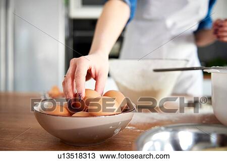 Woman taking egg from bowl in kitchen View Large Photo Image Stock Image - Woman taking egg from bowl in kitchen. Fotosearch