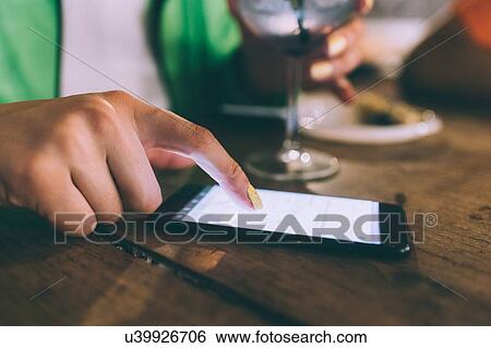 Stock Photograph - Woman texting and having drink in bar. Fotosearch