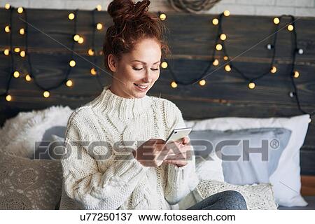Woman texting on bed decorated with Christmas lights View Large Photo Image Stock Photo - Woman texting on bed decorated with Christmas lights. Fotosearch