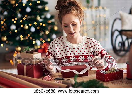 Woman tying ribbon on Christmas present View Large Photo Image Stock Photo - Woman tying ribbon on Christmas present. Fotosearch