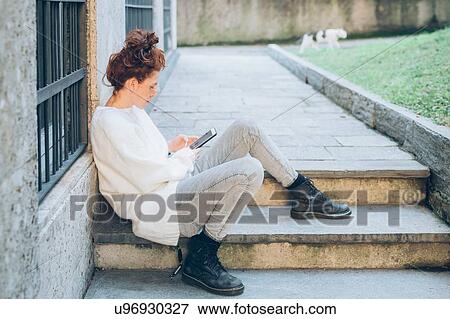 Woman using cellphone on step by building View Large Photo Image Stock Photo - Woman using cellphone on step by building. Fotosearch