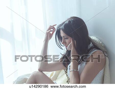 Woman using mobile phone beside window View Large Photo Image Stock Photograph - Woman using mobile phone beside window. Fotosearch
