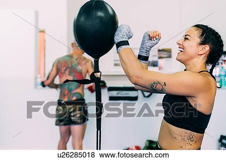 Stock Photo - Woman using punch bag in gym. Fotosearch