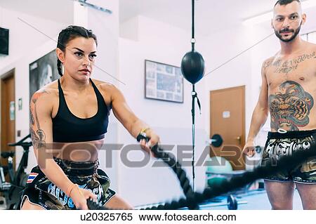 Stock Photography - Woman using rope whips during workout in gym. Fotosearch