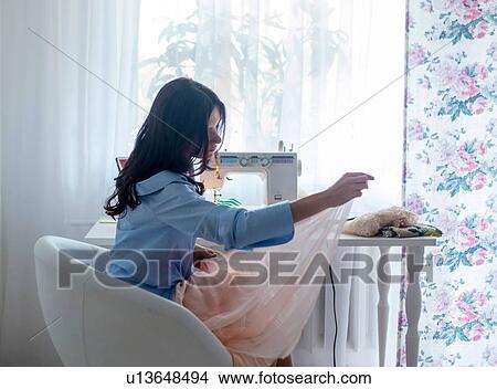 Woman using sewing machine beside window View Large Photo Image Picture - Woman using sewing machine beside window. Fotosearch